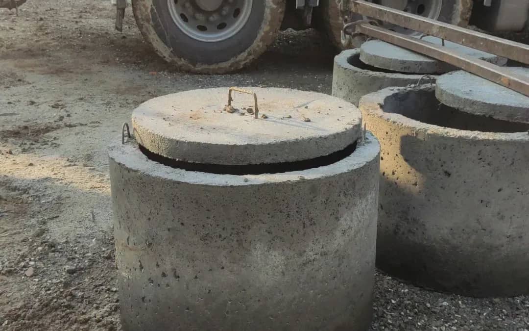 Rozładunek betonowych kręgów Fi 1000 z pokrywą z samochodu z żurawiem HDS na terenie budowy